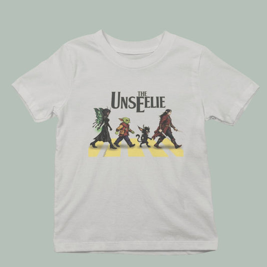 sand colored unisex t-shirt featuring a dark fairy, a goblin, a phooka, and an elven soldier walking across a cross walk in the abbey road Beatles style.  Text reads The Unseelie